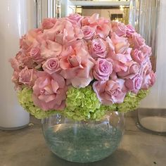 a vase filled with pink and green flowers on top of a table next to a mirror