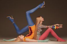 two beautiful young women sitting next to each other on top of one another wearing colorful clothing