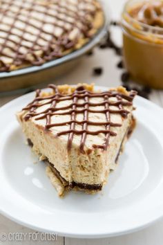 a slice of cheesecake with chocolate drizzled on it sitting on a white plate