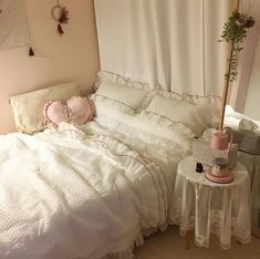 a white bed sitting next to a table with a pink lamp on top of it