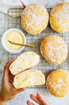 a person holding a doughnut with powdered sugar on it next to other pastries