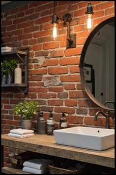 Rustic bathroom with exposed brick wall, round mirror, and sink on a wooden countertop.