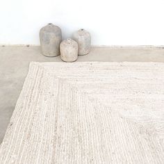 two vases sitting on top of a rug in front of a white wall and floor