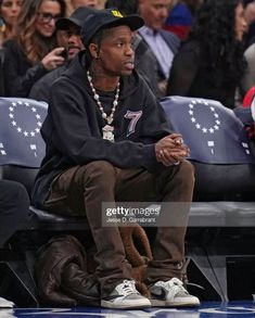 a man sitting in the stands at a basketball game wearing a black sweatshirt and hat