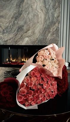 a large bouquet of roses sitting on top of a table next to a fire place