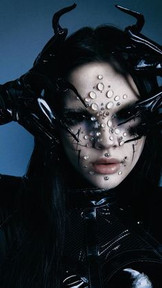 a woman with black hair and horns on her head is covered in water droplets, while she