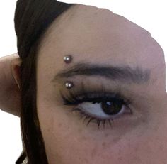 a close up of a person's eye with piercings on their forehead and eyebrows