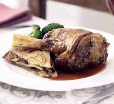 a white plate topped with meat and veggies next to a glass of wine