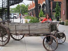 a woman is sitting in an old wooden wagon