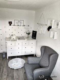 a chair and dresser in a small room with white walls, wood flooring and black and white wallpaper