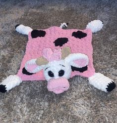 a crocheted cow is laying on the carpet