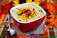 a red bowl filled with soup sitting on top of a table next to fall leaves