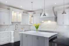 a large kitchen with white cabinets and marble counter tops, along with a center island