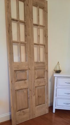 two wooden doors sitting on top of a hard wood floor next to a white dresser