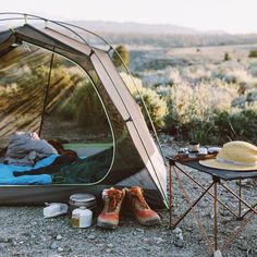 a tent with the door open next to a table and hat on top of it