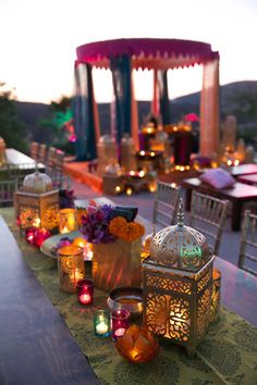 a long table topped with lots of lit candles and vases filled with colorful flowers