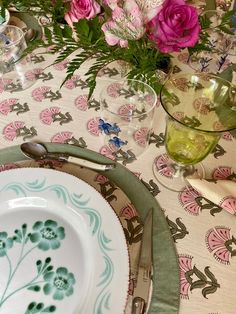 the table is set with plates, silverware and flowers