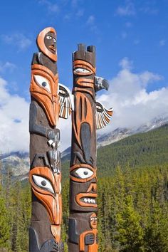 two totems in the woods with mountains in the background