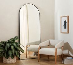 a chair and mirror in a room with wooden flooring next to a potted plant