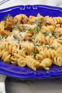 a blue plate topped with pasta covered in sauce