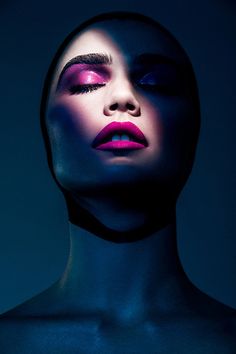 a woman's face is lit up with blue and pink makeup