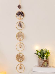 a wall hanging with several circular beads and stones on it next to a potted plant