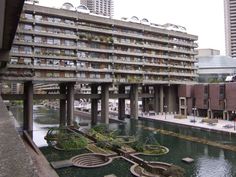 an apartment building next to a body of water with plants growing out of the balconies