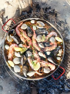 a pan filled with seafood and clams on top of a grill