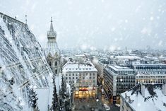 snow falling on the roofs of buildings and spires in a snowy cityscape