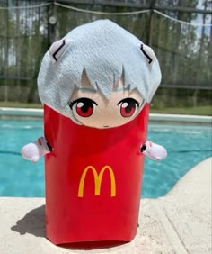 a mcdonald's character is sitting in front of a swimming pool wearing a costume