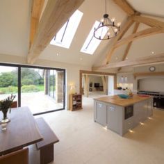 a large open kitchen and dining room area with wooden beams on the ceiling, glass doors leading to an outside patio