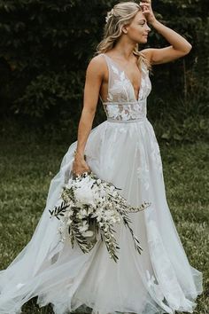 a woman in a white wedding dress holding a bouquet and looking at the camera with her hand on her head