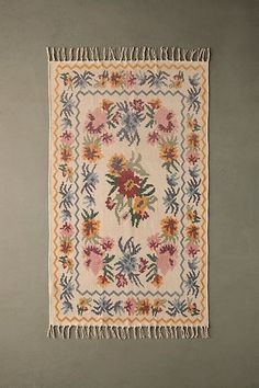 a rug with flowers and fringes hanging on the wall