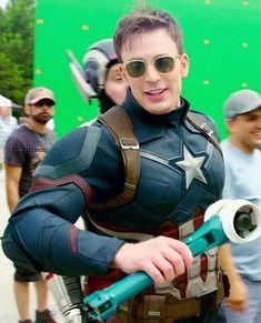 a man dressed as captain america holding a giant wrench in front of a group of people