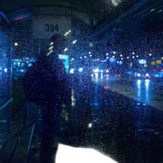 a person standing in front of a window on a rainy day with rain falling down