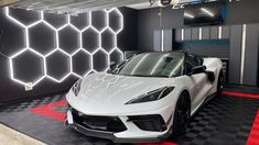 a white sports car is parked in front of a black and red checkered wall