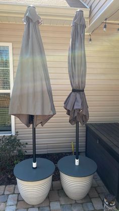 two umbrellas sitting on top of blue bases in front of a white house with windows