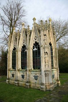 an old building with many windows and statues on the front, sitting in a grassy area