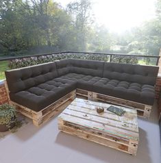 a couch made out of wooden pallets sitting on top of a patio next to a table