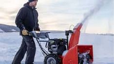 a man standing next to a snow blower