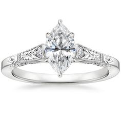 a white gold engagement ring with an oval cut diamond and filigrees on the band