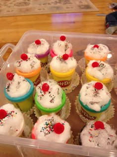 cupcakes with white frosting and sprinkles in a plastic container