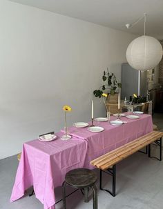 a long table with plates and cups on it in front of a white ball hanging from the ceiling