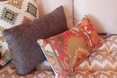 three pillows sitting on top of a couch with different colors and patterns around them,