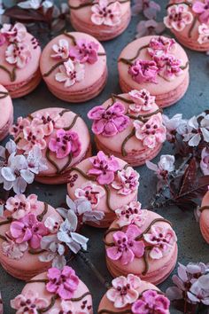 pink and white decorated cookies sitting on top of a table next to purple flower decorations