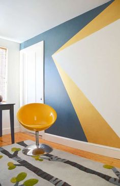 a yellow chair sitting on top of a rug in front of a blue and white wall