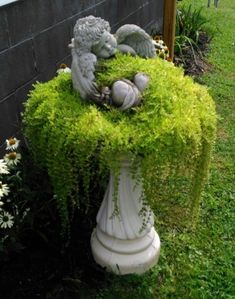 a white vase with some plants growing out of it's sides in the grass