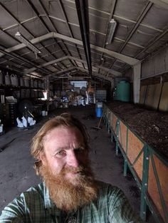 a man with a long beard is sitting in an old building and looking at the camera