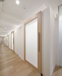 an empty hallway with white walls and wooden doors