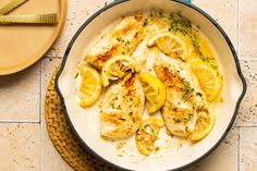 a skillet filled with chicken and lemons on top of a tiled countertop